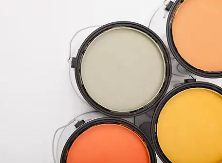 Four open paint cans arranged in a cluster, containing light gray, orange, yellow, and peach paints, set against a white background—perfect inspiration for Property Owners Association renovation projects.